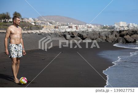 Confident Adult Man Standing On Black Sand Beach Near Coastal City Skyline Confident Adult Man Standing On Black Sand Beach Near Coastal City Skyline 139027752