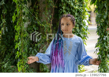 A natural portrait of a young woman standing amid lush greenery. 139027766