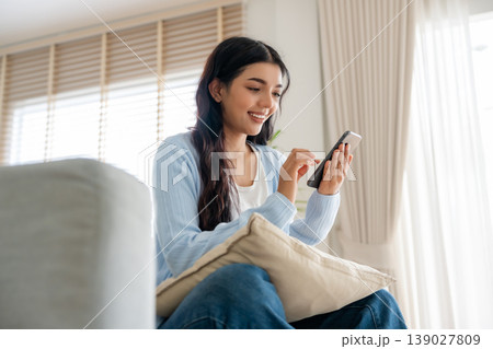 Smiling pretty young Asian woman sitting on cozy couch 139027809