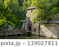Historic Stone Building With Arch Bridge Over Calm River Surrounded By Green Forest 139027811