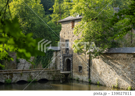Historic Stone Building With Arch Bridge Over Calm River Surrounded By Green Forest Historic Stone Building With Arch Bridge Over Calm River Surrounded By Green Forest 139027811
