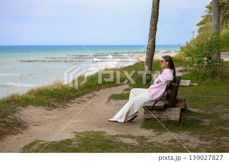 Young Woman Relaxing On Coastal Path Bench With Ocean View Background 139027827