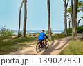 Woman riding bicycles along a sandy forest path near the sea. 139027831
