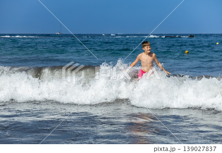 Young Boy Playing In Ocean Surf On Bright Sunny Summer Day Young Boy Playing In Ocean Surf On Bright Sunny Summer Day 139027837