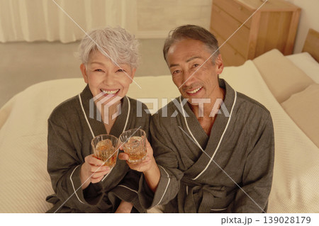 寝室でウイスキーを飲むシニア夫婦　ポートレート　カメラ目線 139028179