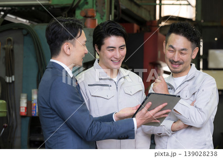 工場でタブレットを使い3人で打ち合わせする作業員とビジネスマンの現場、dxやIT、AI化の機械の導入 139028238