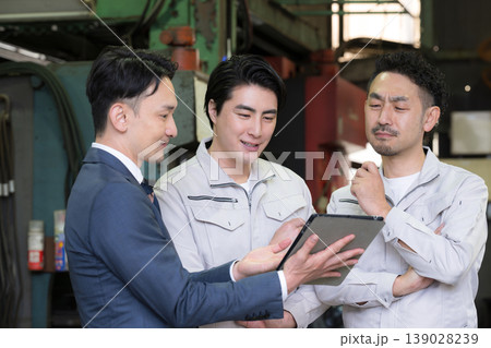 工場でタブレットを使い3人で打ち合わせする作業員とビジネスマンの現場、dxやIT、AI化の機械の導入 139028239