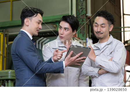 工場でタブレットを使い3人で打ち合わせする作業員とビジネスマンの現場、dxやIT、AI化の機械の導入 139028650