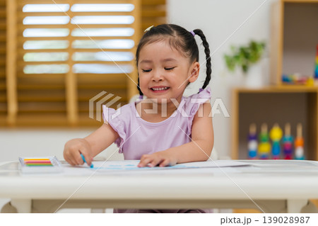 happy preschool child girl drawing and painting with colorful oil pastels on paper 139028987
