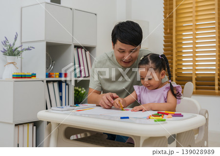 Caption/Description: father and child girl drawing and painting with colorful oil pastels on paper 139028989