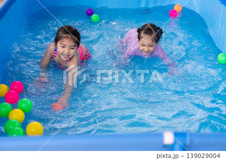 happy preschool child girl playing together with her sister in outdoor portable swimming pool in backyard happy preschool child girl playing together with her sister in outdoor portable swimming pool in backyard 139029004