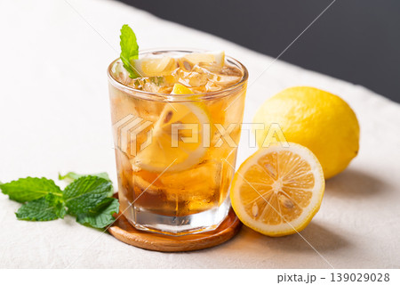 Refreshing iced lemon tea in a glass with sliced lemon and mint leaves, cold summer drink Refreshing iced lemon tea in a glass with sliced lemon and mint leaves, cold summer drink 139029028