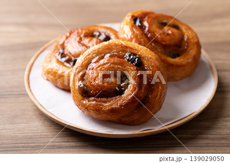 French Pain au Raisin, Cinnamon Raisin Swirl on plate with wooden background, Delicious breakfast French Pain au Raisin, Cinnamon Raisin Swirl on plate with wooden background, Delicious breakfast 139029050