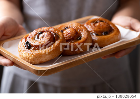 French Pain au Raisin, Cinnamon Raisin Swirl on plate holding by woman hand, Delicious breakfast French Pain au Raisin, Cinnamon Raisin Swirl on plate holding by woman hand, Delicious breakfast 139029054