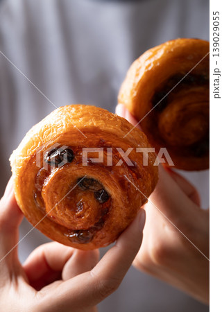 French Pain au Raisin, Cinnamon Raisin Swirl holding by hand and eating, Delicious breakfast 139029055