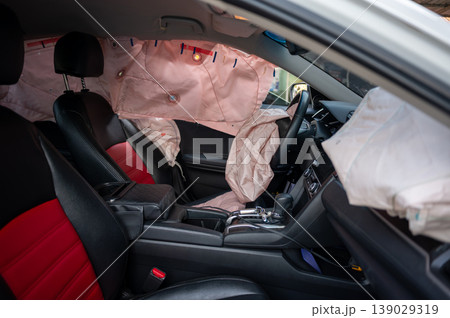 Deployed airbags inside modern car interior with black and red seats Deployed airbags inside modern car interior with black and red seats 139029319