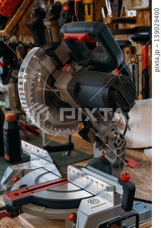 Miter saw. Woodworking equipment. Electric carpentry device with circular metal blade in clear safety plastic on measuring scale base. Miter saw. Woodworking equipment. Electric carpentry device with circular metal blade in clear safety plastic on measuring scale base. 139029400