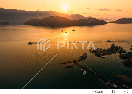 Beautiful aerial view of luxury catamarans and local fishing boats anchored in a calm tropical bay during golden hour. Beautiful aerial view of luxury catamarans and local fishing boats anchored in a calm tropical bay during golden hour. 139031107