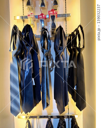 Yogyakarta, Indonesia - March 18th 2026: Collection of stylish neckties in shades of blue, grey, and black, neatly displayed on a store rack under warm lighting Yogyakarta, Indonesia - March 18th 2026: Collection of stylish neckties in shades of blue, grey, and black, neatly displayed on a store rack under warm lighting 139032237