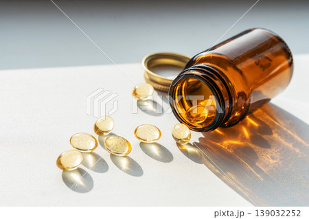 Glass dark bottle spilling vitamin pills, symbolizing daily health and wellness supplements, enhancing personal healthcare. Pills spilling from bottle for health treatments 139032252
