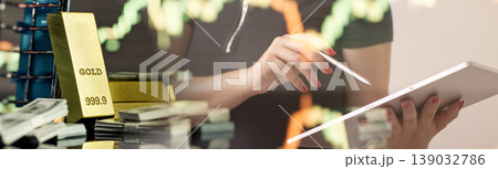 Double exposure of a female investor using a digital tablet with gold bullion bars, cash money, and stock market trading charts. Online wealth management concept. Double exposure of a female investor using a digital tablet with gold bullion bars, cash money, and stock market trading charts. Online wealth management concept. 139032786
