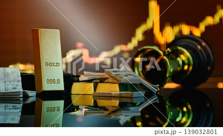 Gold investment and financial success concept: 999.9 gold bars, dollar cash, and a trophy against a blurred stock market chart. 139032801