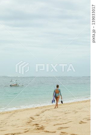 Person walking on sand near water with a boat in view 139033017