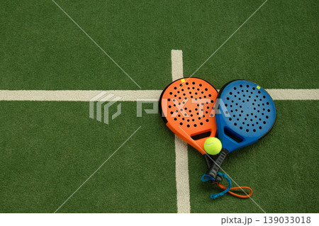 Padel rackets and a ball are placed on the court for play 139033018