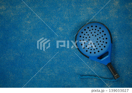 Padel racket rests on blue surface in sunny setting Padel racket rests on blue surface in sunny setting 139033027