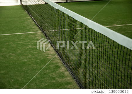 Padel court features net and green turf for summer play Padel court features net and green turf for summer play 139033033