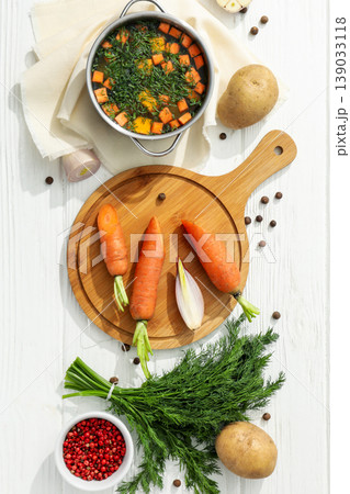 Carrots, potatoes, and a bowl of soup sit on a table Carrots, potatoes, and a bowl of soup sit on a table 139033118