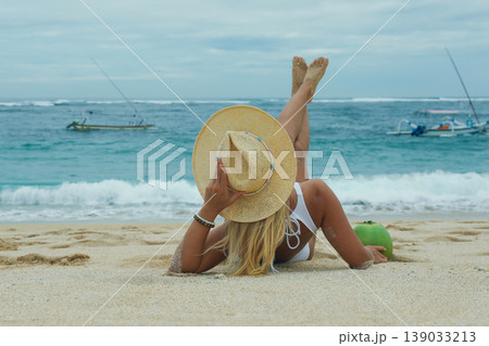 Woman on beach sand with a hat and coconut 139033213