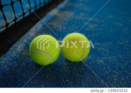 Padel balls sit on bright blue court surface by net 139033232