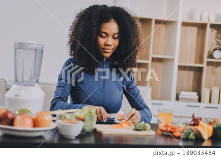 Young nutritionist showing bell peppers during an online video call consulting about healthy eating, sitting at home at a table with vegetables, laptop and measuring tape Young nutritionist showing bell peppers during an online video call consulting about healthy eating, sitting at home at a table with vegetables, laptop and measuring tape 139033484