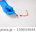 Gloved Hand Drawing Red Smear Curve On White Surface, Experimental MarkMaking, Controlled Swipe, Vivid 139033644