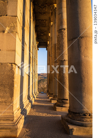 Long row of massive stone pillars under golden afternoon sun Long row of massive stone pillars under golden afternoon sun 139034347