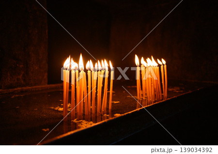 Lit candles in dark church interior, prayer and spirituality concept 139034392