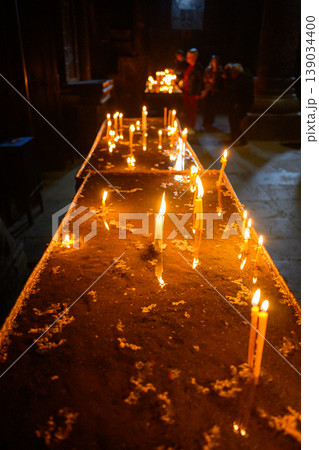 Lit candles in dark church interior, prayer and spirituality concept Lit candles in dark church interior, prayer and spirituality concept 139034400