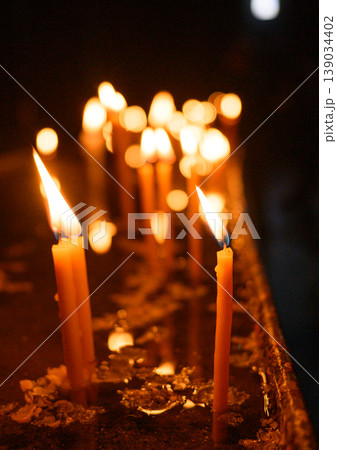 Lit candles in dark church interior, prayer and spirituality concept Lit candles in dark church interior, prayer and spirituality concept 139034402