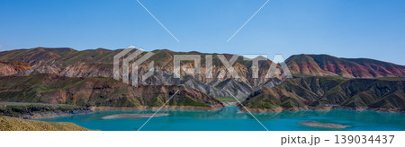 Landscape with bright blue lake surrounded by layered mountain slopes 139034437