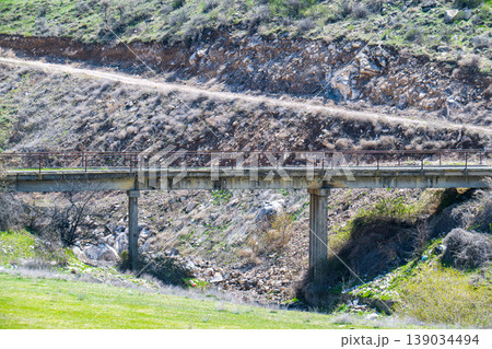 Rugged mountain path crosses concrete bridge Rugged mountain path crosses concrete bridge 139034494
