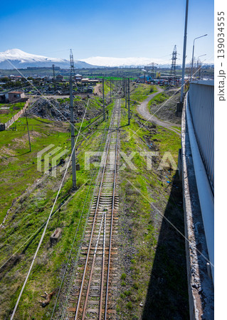 Railway lines run through open grassland with distant snowy peaks and clear sky Railway lines run through open grassland with distant snowy peaks and clear sky 139034555