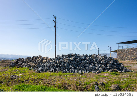 Stack of rough, gray stones rests in sunny field Stack of rough, gray stones rests in sunny field 139034585