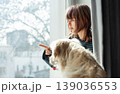 Girl and dog pointing outside window observing winter day 139036553