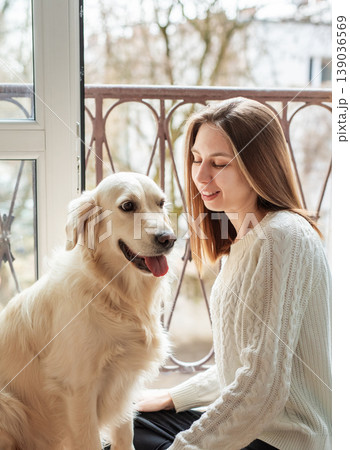 Woman and golden retriever dog sharing happy moment indoors Woman and golden retriever dog sharing happy moment indoors 139036569