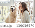 Woman bonding with golden retriever dog by window 139036570