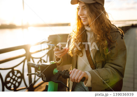 Woman driving electric scooter through city. Ecological transportation. Travel, tourism concept. Woman driving electric scooter through city. Ecological transportation. Travel, tourism concept. 139036939
