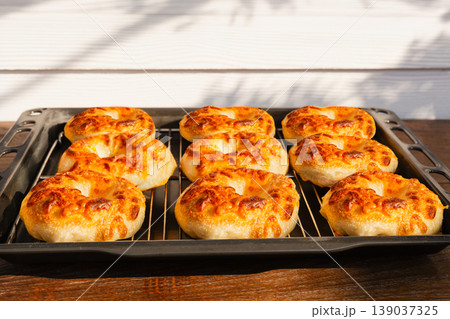 Freshly baked bagels with melted cheese topping on a cooling rack and baking tray. Freshly baked bagels with melted cheese topping on a cooling rack and baking tray. 139037325