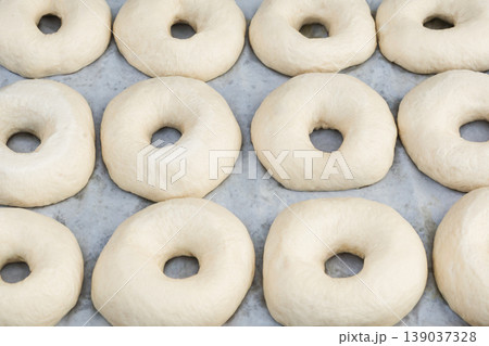 Top view of raw dough rings on baking paper for homemade bagels. Top view of raw dough rings on baking paper for homemade bagels. 139037328
