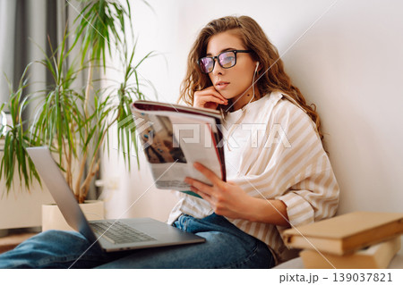 Young woman studying at home with modern laptop, books. Relaxes in the living room. Relax concept. 139037821